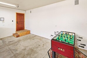Ett rum med ett fotbollsspel, en trädörr och ett mattbeklätt golv.