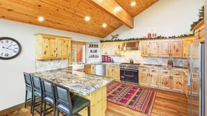 Una cocina con armarios de madera, encimera de granito, estufa y refrigerador.