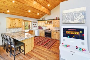 A kitchen with wooden cabinets, a granite countertop, and a built-in oven. - Luxury! Stunning Views! Minutes from Bear Mountain! Air Conditioning! PET FRIENDLY! HOT TUB ! EV Charger! Pool Table! Foosball! Video Arcade Game! (Big Bear Lake)