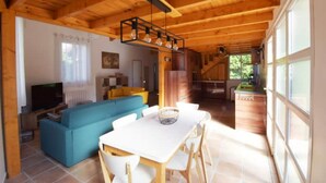 A wooden interior with a sofa, dining table, and chairs.