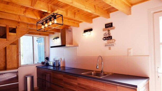 A modern kitchen with wooden beams, a stainless steel sink, and a built-in oven.