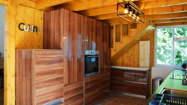 A compact kitchen with wooden cabinetry, a built-in oven, and a staircase leading to an upper level.