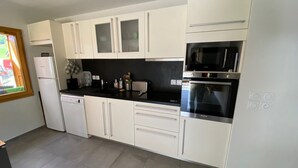 A modern kitchen with white cabinets, a black countertop, a dishwasher, a microwave, and an oven.