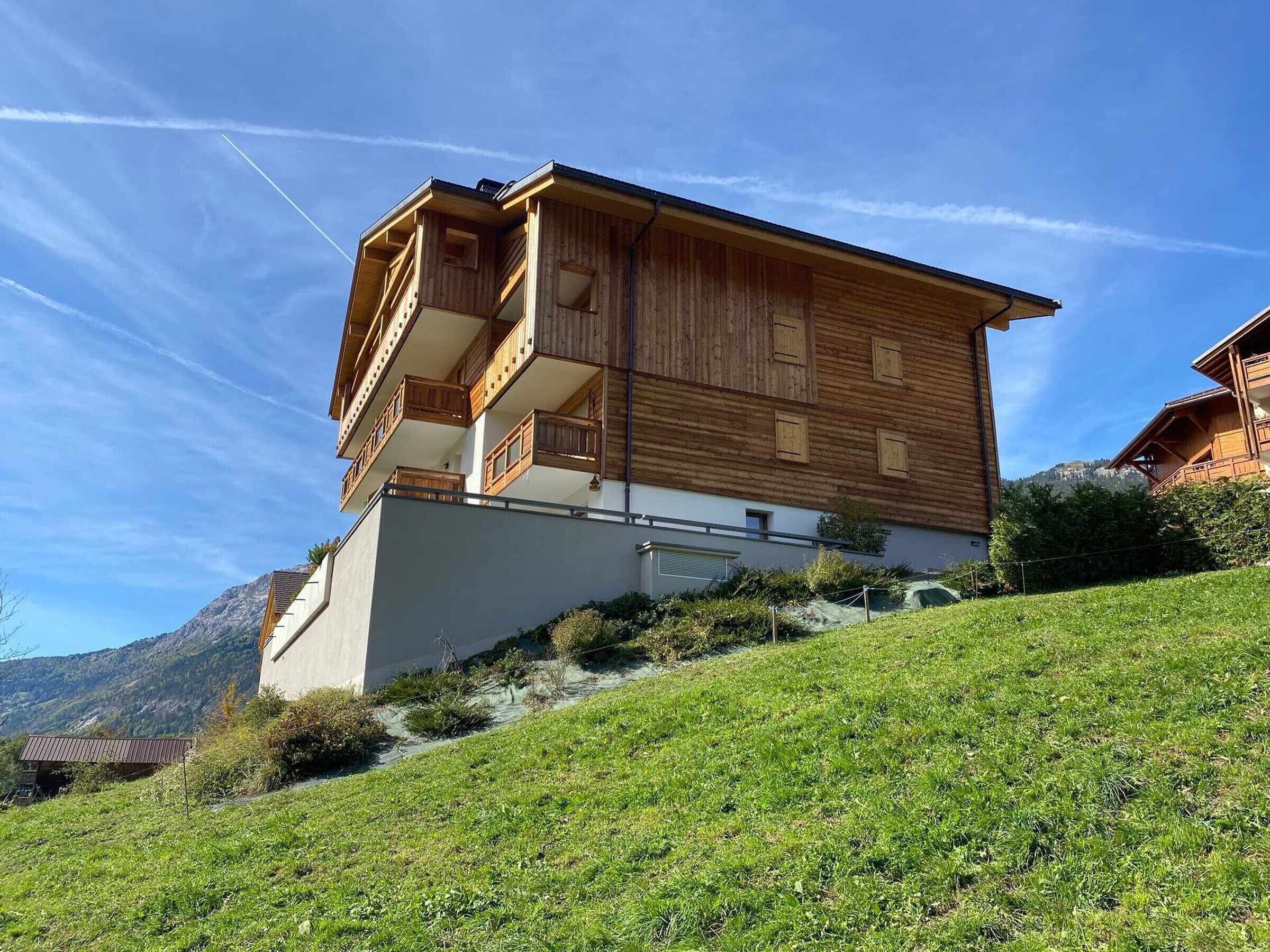 Un chalet en bois doté d’un balcon, situé dans un cadre montagneux.