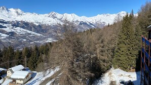 Un refugio de montaña con vistas a picos nevados, rodeado de árboles de hoja perenne.