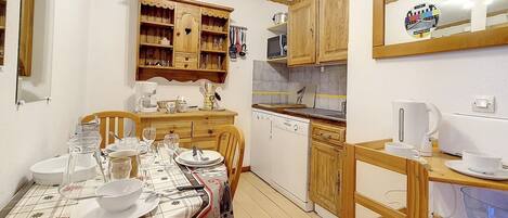 Cocina compacta con armarios de madera, microondas y lavavajillas.