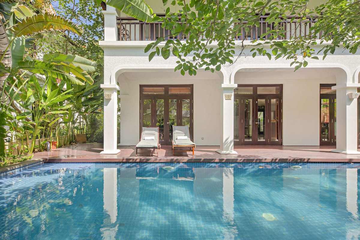 A poolside area with two lounge chairs and a clear blue pool.