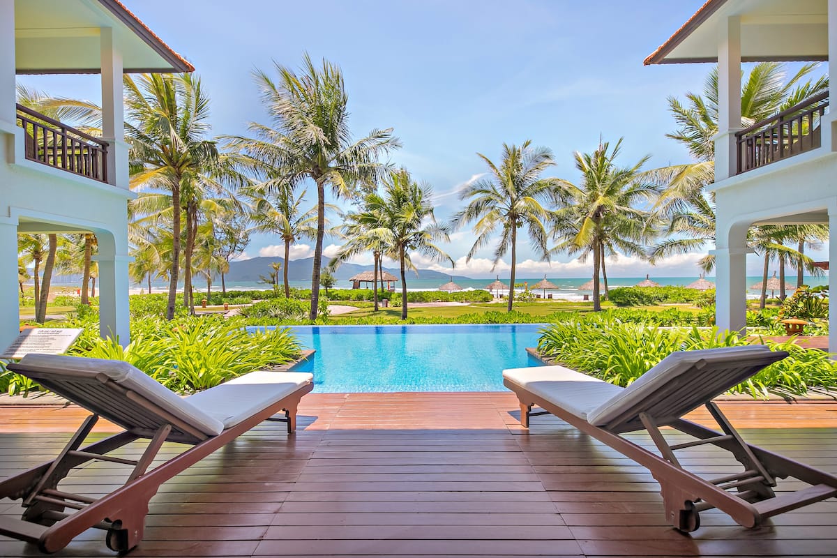 A poolside area with lounge chairs and a view of the ocean.