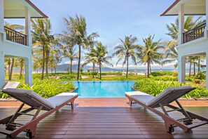 Un espace aménagé au bord de la piscine, avec des chaises longues et une vue sur l’océan.