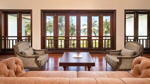 A spacious room with a large window, two armchairs, a sofa, and a coffee table. - Resort Villa Da Nang By Abogo (Da Nang)