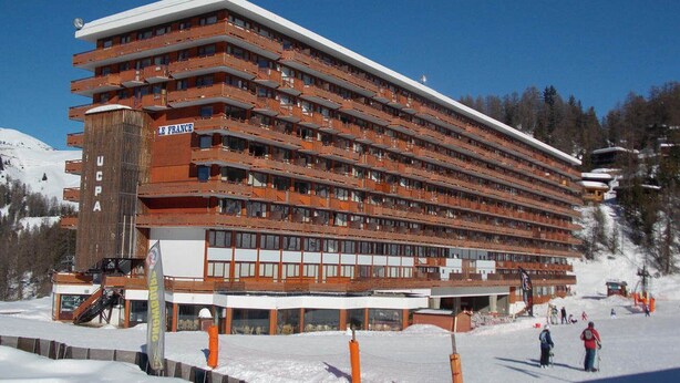 A multi-story hotel with balconies, a ski lift, and a snowy landscape. - Bright studio with balcony, ski-in/ski-out, sleeps 4 (La Plagne)