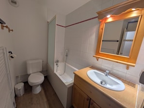 Une salle de bain comprenant des toilettes, une baignoire, un lavabo et un miroir.