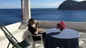 Un balcó amb vista al mar i una taula petita amb un ram de flors.