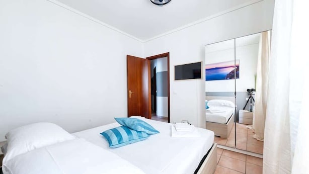 A hotel room with a bed, a wardrobe, a mirror, and a painting on the wall.