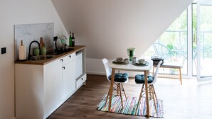 Una cocina moderna con comedor, que presenta un armario blanco, un salpicadero de mármol y una mesa de comedor con sillas.