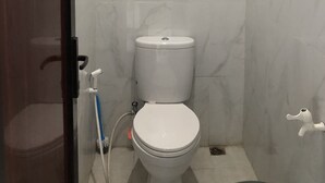 Een badkamer met een toilet, een dweil en een handdroger.
