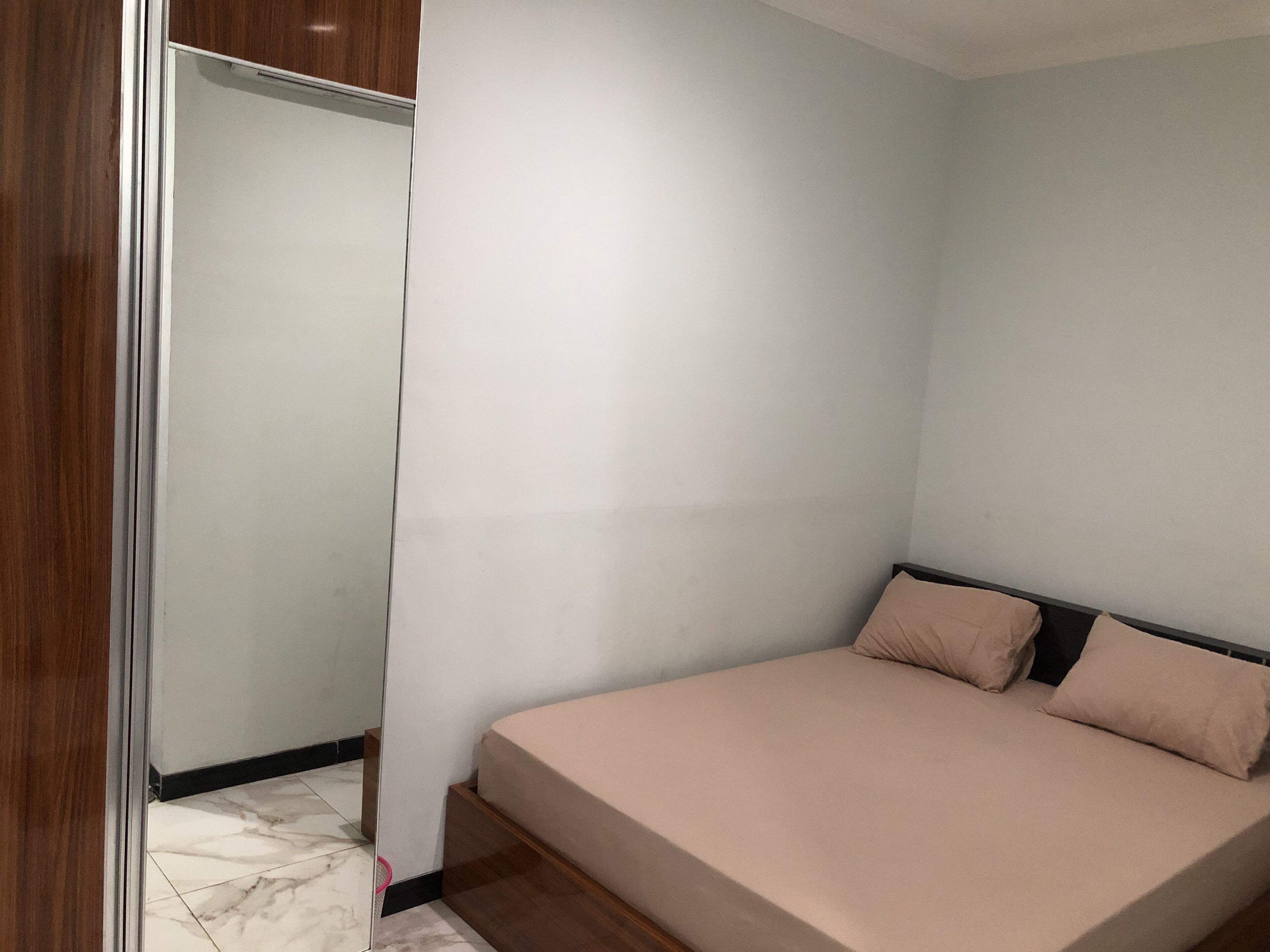 Un dormitorio con cama, armario de madera y suelo de baldosas.