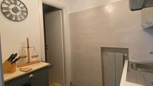 Une cuisine équipée d’une cuisinière, d’un évier, d’une balance et de luminaires suspendus.