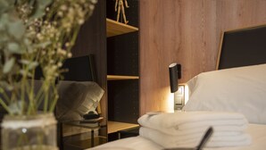 A neatly made bed with white linens, a bedside lamp, and a glass of orange juice on a bedside table. - Neobeds A - Modern and elegant 1BR Apt near Old Town and Turia park (València)