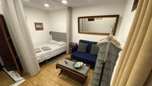 Une petite pièce comprenant un lit, un canapé, une table basse et un miroir.