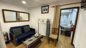 Un salon avec un canapé bleu, une table basse en bois, un fauteuil, un porte-manteau et un miroir au mur.