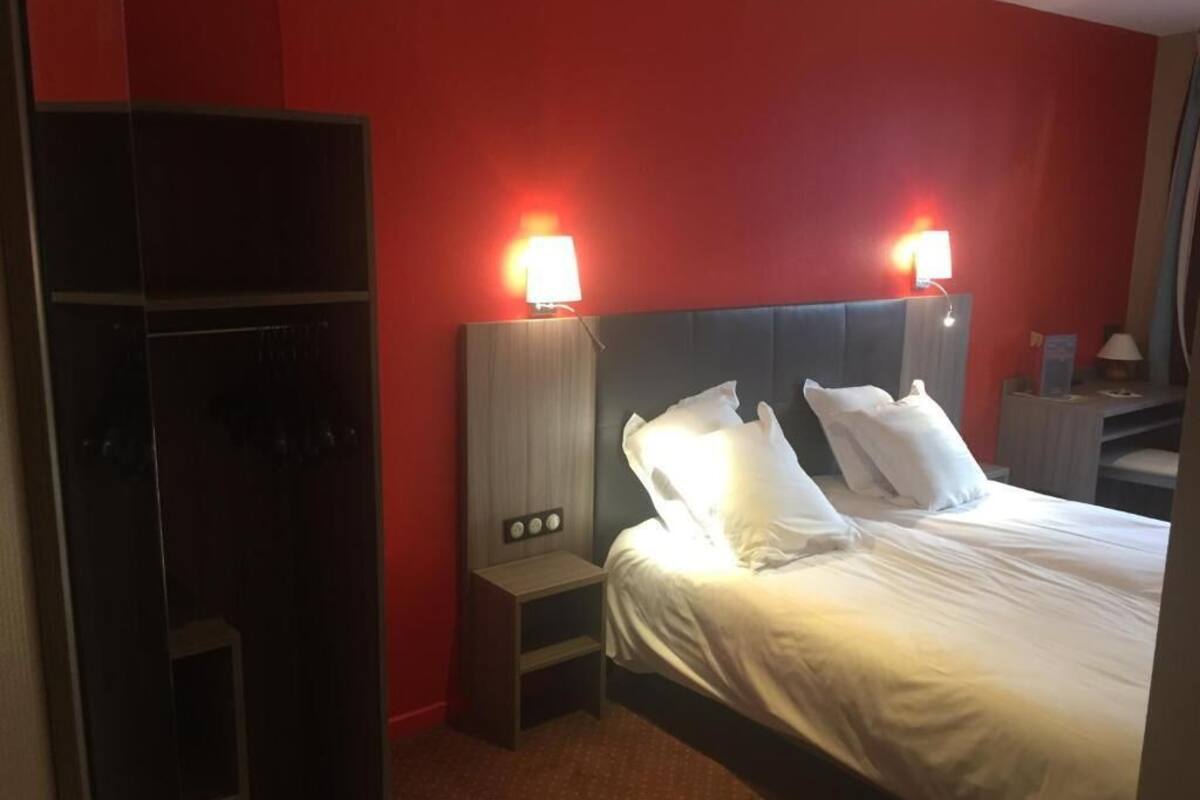 A hotel room with a bed, two bedside lamps, a nightstand, and a wardrobe.
