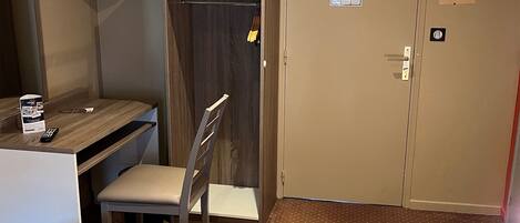 A hotel room with a bed, a desk with a chair, a television, and a wardrobe.