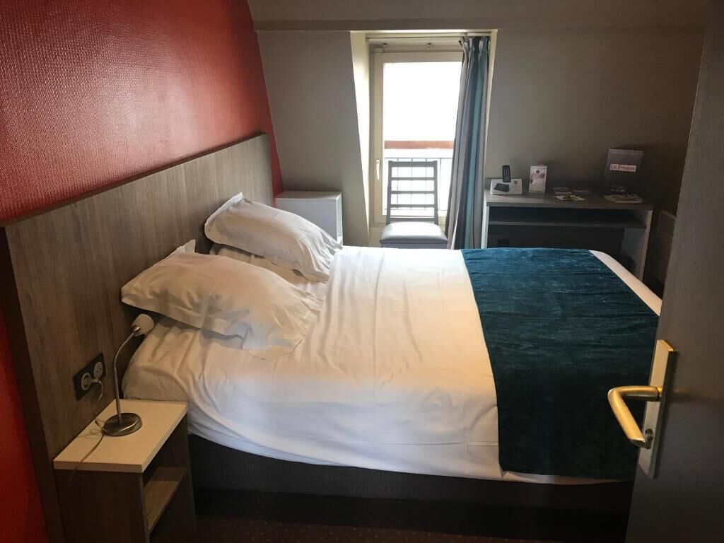 Une chambre d’hôtel comprenant un lit, une table de chevet et un bureau avec une chaise.