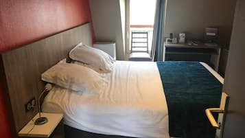 Une chambre d’hôtel comprenant un lit, une table de chevet et un bureau avec une chaise.