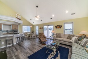 A spacious living area with a kitchen, a dining table, and a large window offering a view.