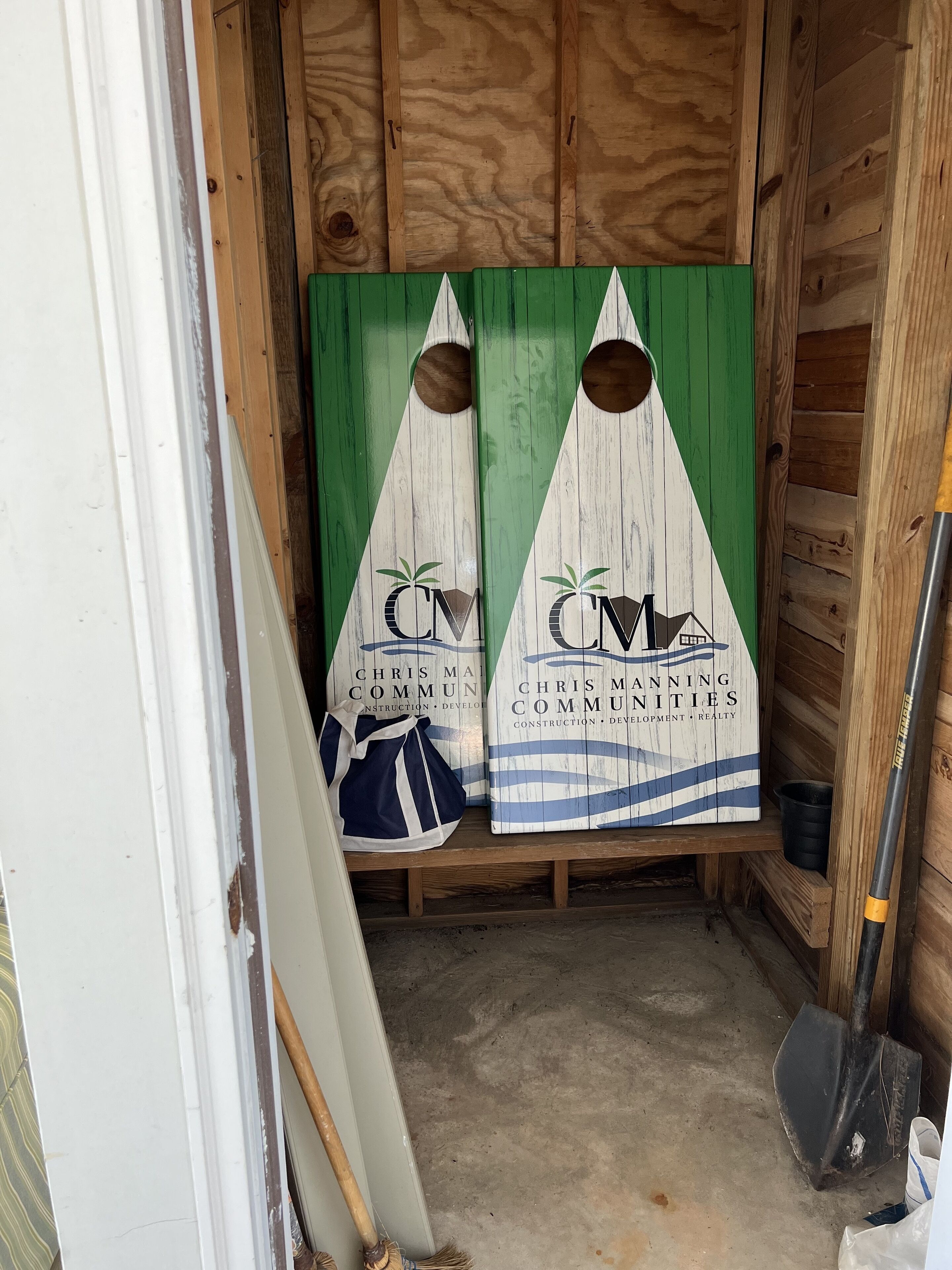 Un intérieur en bois avec deux panneaux verts et blancs indiquant « Chris Manning Communities », un sac bleu et une pelle.