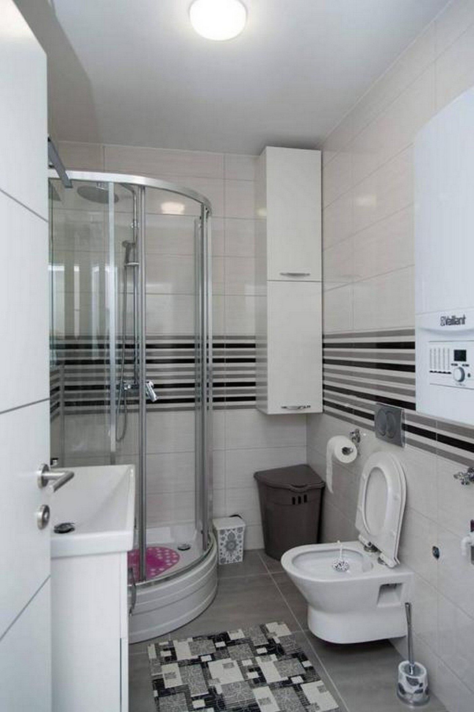 A modern bathroom with a glass-enclosed shower, a toilet, and a sink.