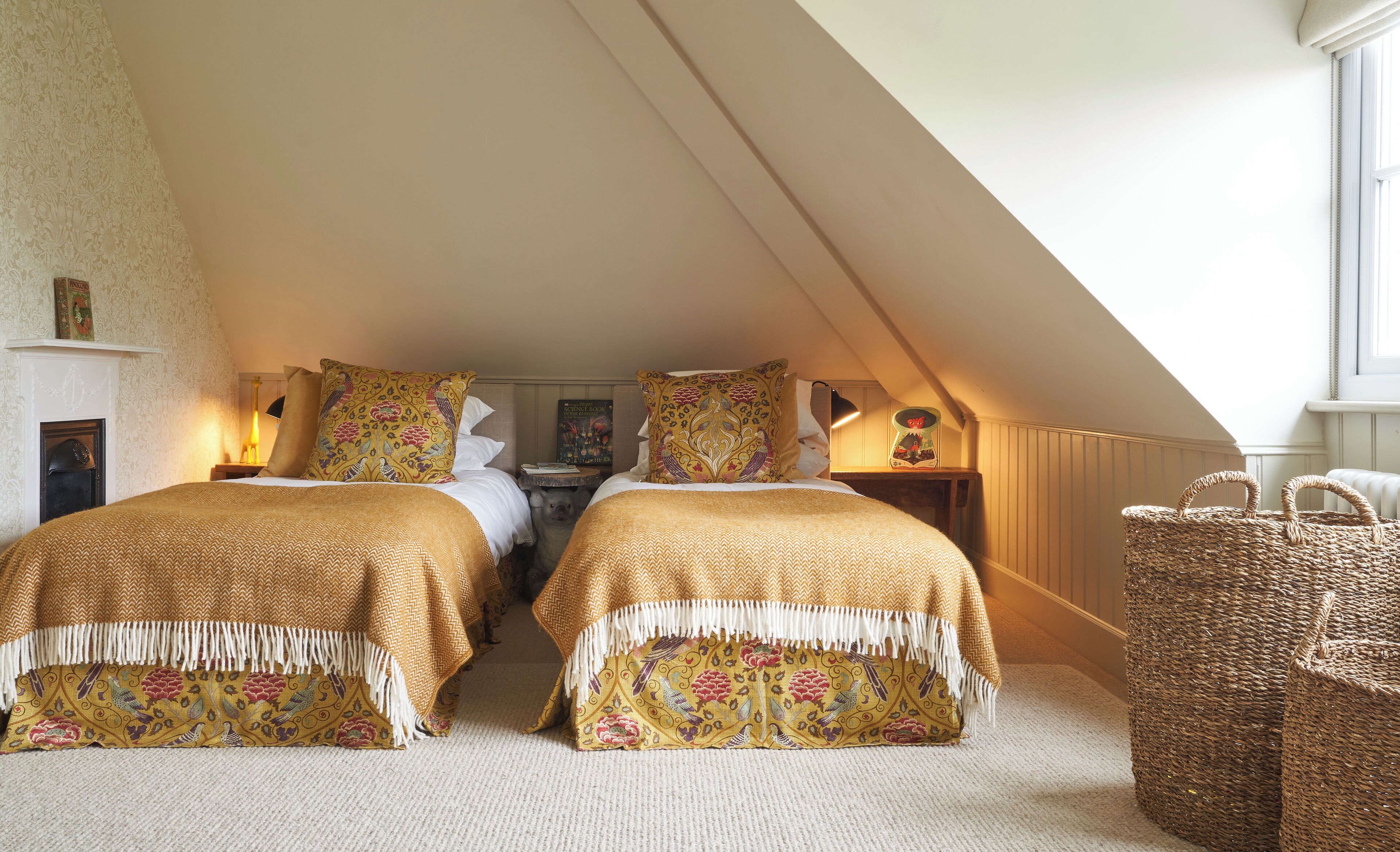 A bedroom with two beds, a fireplace, and a large window.