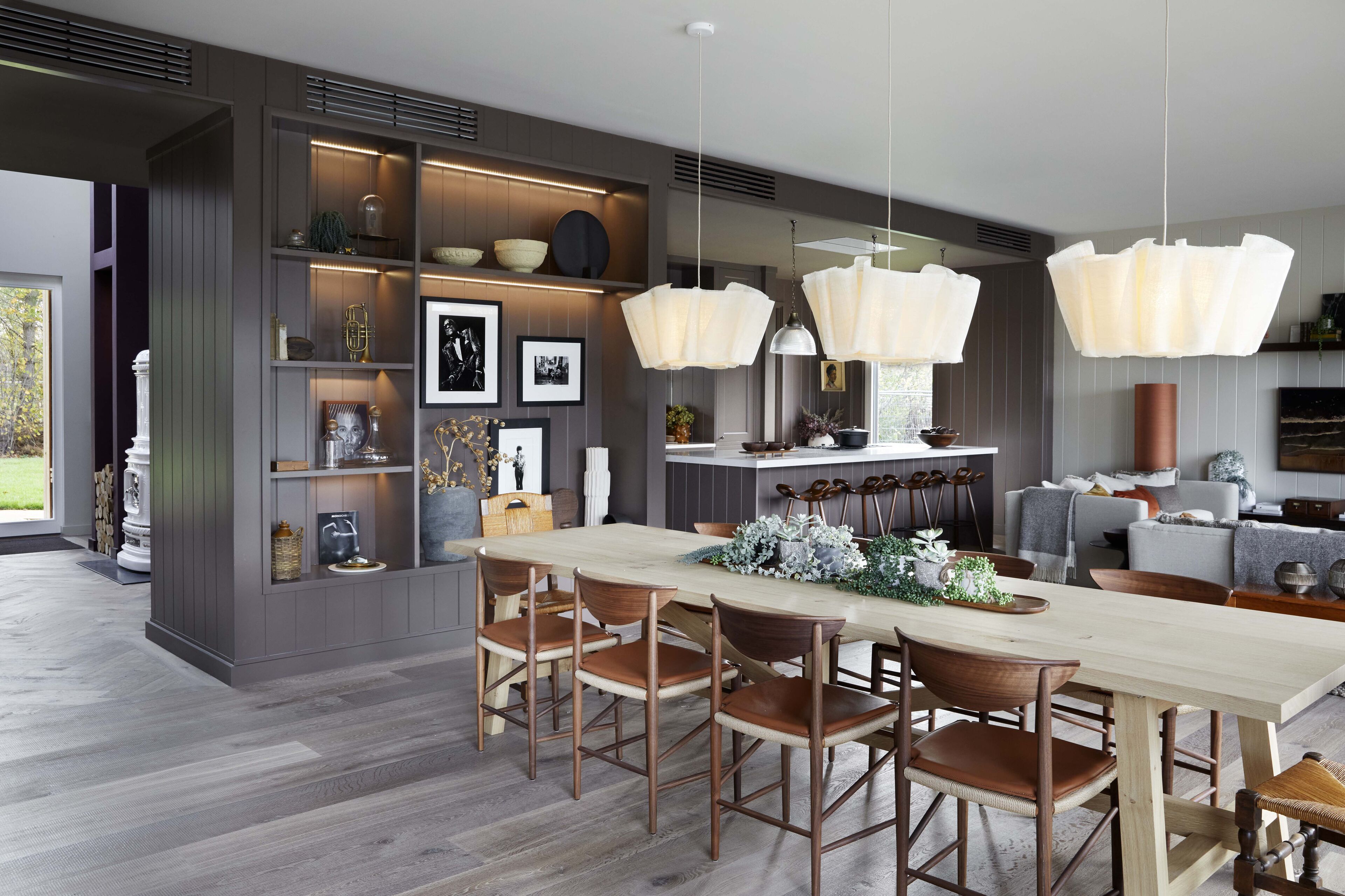 Una cocina moderna con una mesa de comedor de madera, estantes empotrados e iluminación colgante.