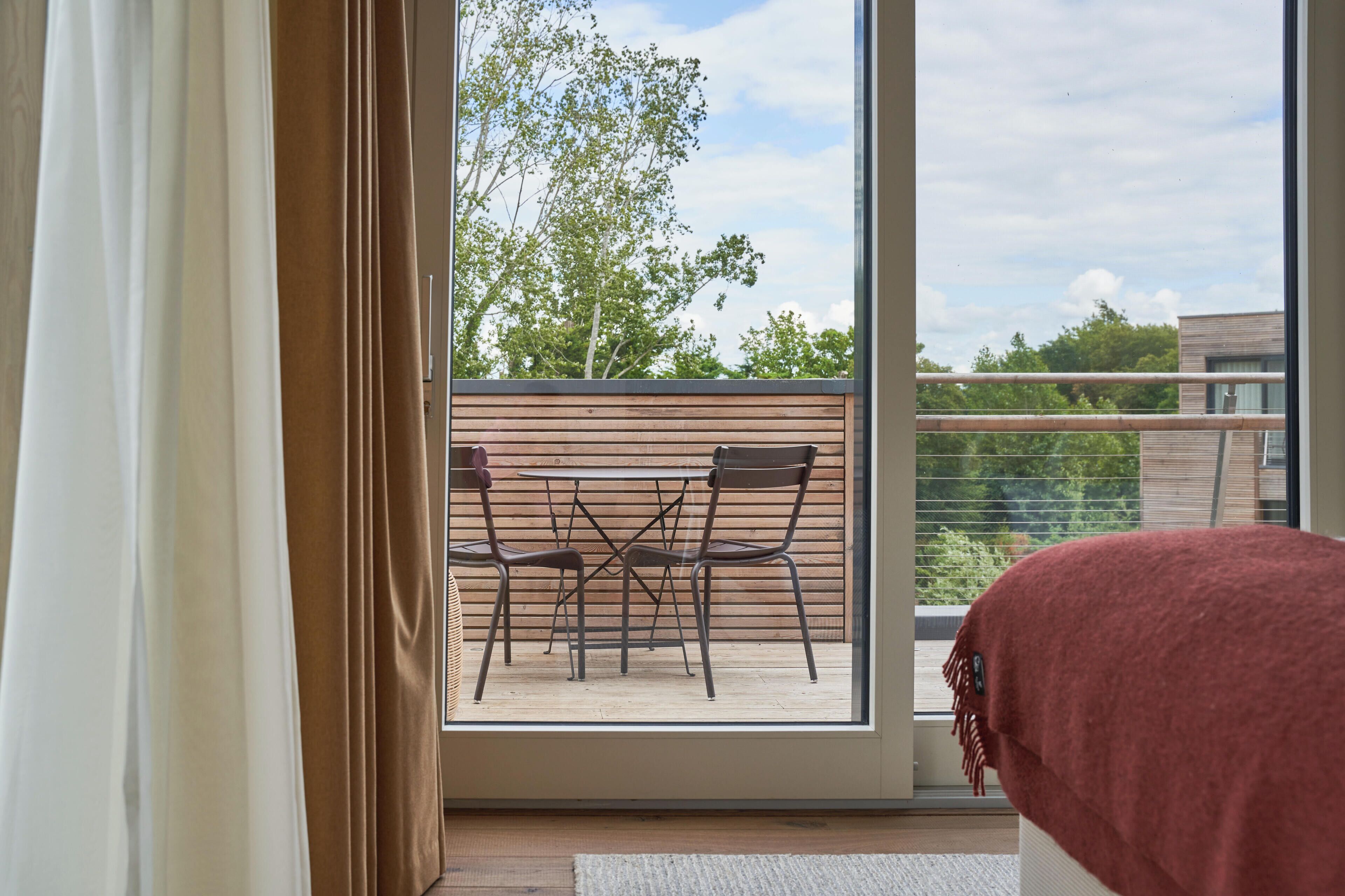 Ein Zimmer mit einer großen Glasschiebetür, die auf einen Balkon mit Tisch und Stühlen führt.