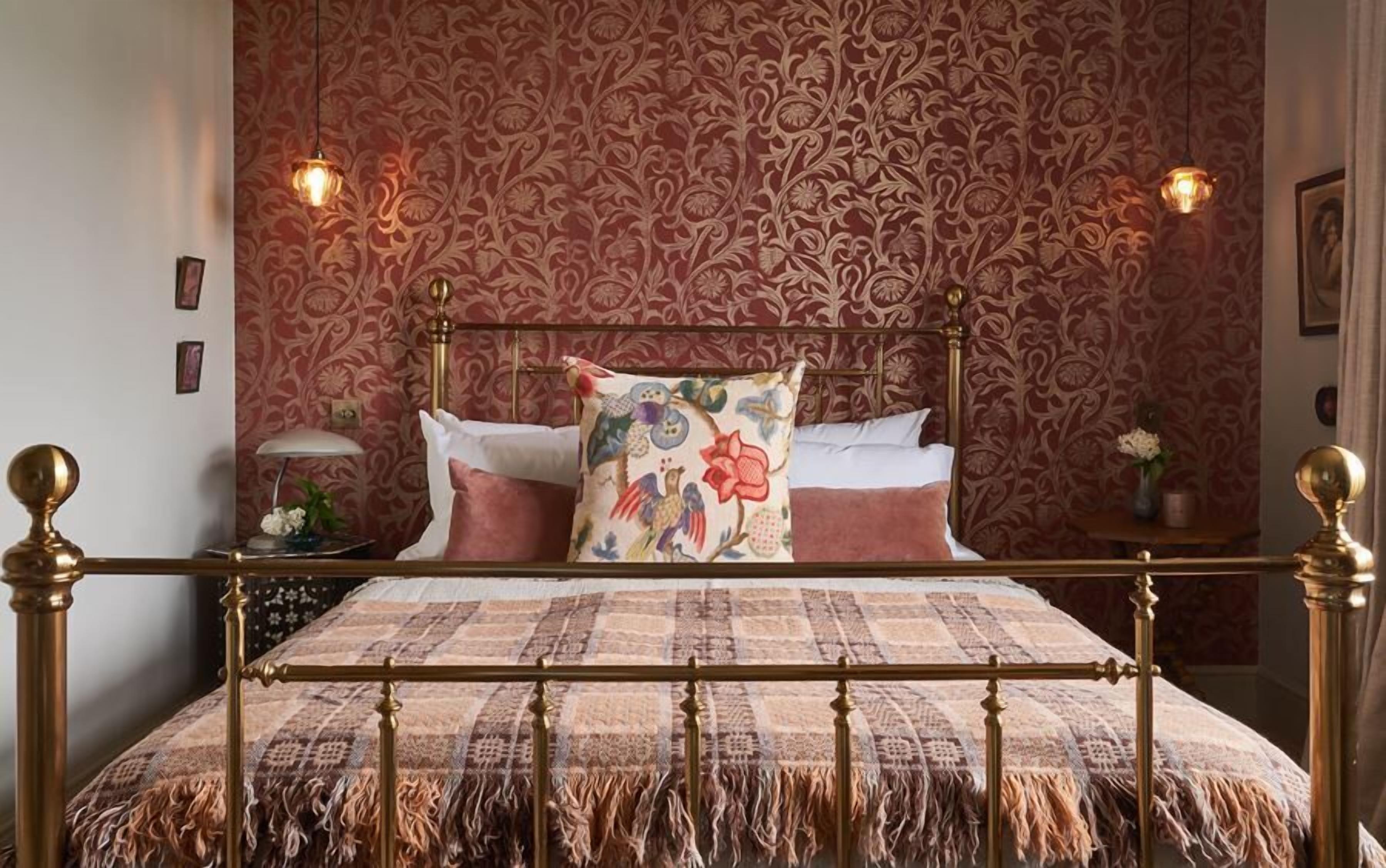 A bed with a patterned bedspread, a decorative pillow, and a nightstand with a lamp.