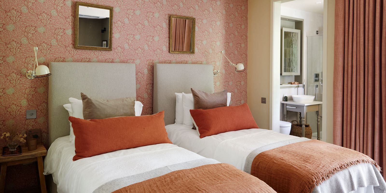 A hotel room with two beds, a bathroom, and a mirror.