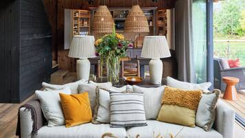 Una sala de estar acogedora con un sofá, lámparas y un jarrón de flores.