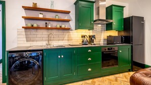 Una cocina con armarios verdes, lavadora, microondas y refrigerador.