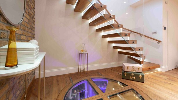 Ein modernes Interieur mit einer Wendeltreppe, einem runden Glastisch und einem kleinen Hocker.