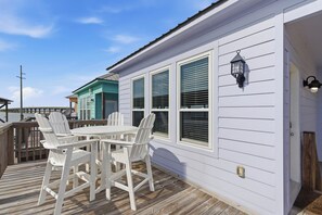 A white house with a deck, a table with chairs, and a lantern. - Unit 043 - Fish Camp 015 - Pool - Community Boat Ramp - Cute as can be! (Dauphin Island)