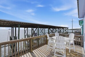 A wooden deck with white chairs and a table, overlooking a body of water. - Unit 043 - Fish Camp 015 - Pool - Community Boat Ramp - Cute as can be! (Dauphin Island)