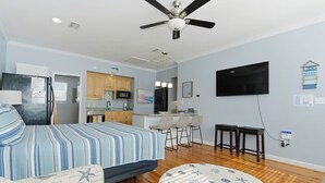A bedroom with a bed, a desk, a TV, and a kitchenette. - Unit 043 - Fish Camp 015 - Pool - Community Boat Ramp - Cute as can be! (Dauphin Island)