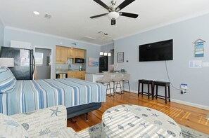 Une chambre avec un lit, un bureau, une télévision et un coin cuisine.
