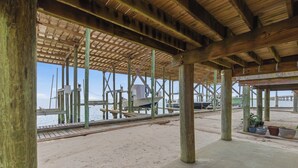 A wooden pier structure with a sandy beach and a boat docked at the end. - Unit 043 - Fish Camp 015 - Pool - Community Boat Ramp - Cute as can be! (Dauphin Island)