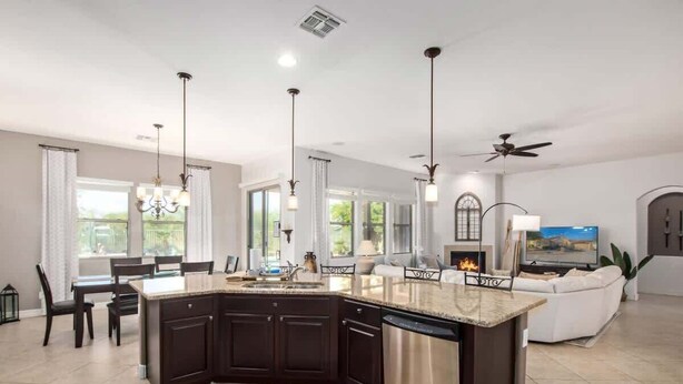A modern kitchen with dark cabinetry, a stainless steel dishwasher, and a central island.