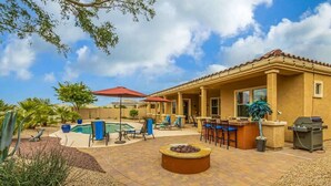 A patio area with a pool, outdoor seating, and a barbecue grill.