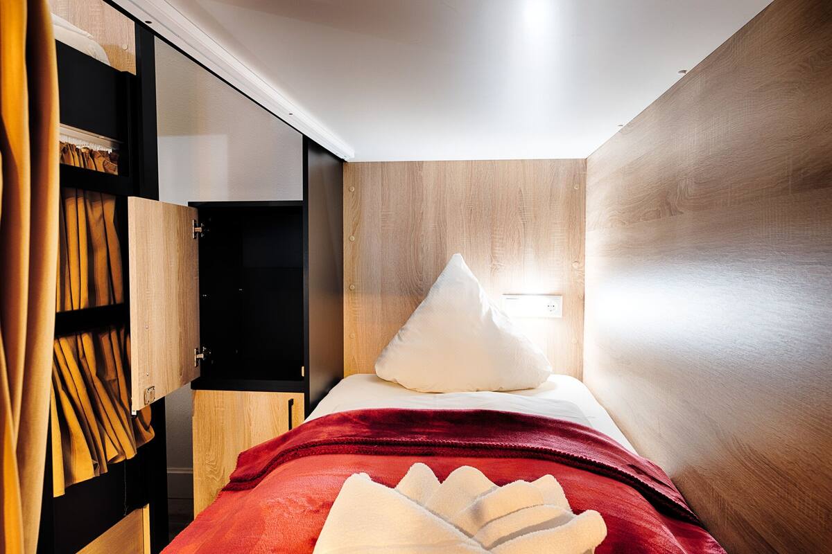 Ein kleines Schlafzimmer mit einem Bett, einem Kleiderschrank und einer roten Decke.
