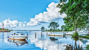 A calm lake with boats docked at the shore, surrounded by trees and a clear sky.