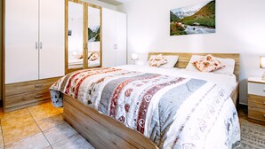 Ein Schlafzimmer mit einem großen Bett, einem Holzschrank und einem Gemälde von einer Berglandschaft.